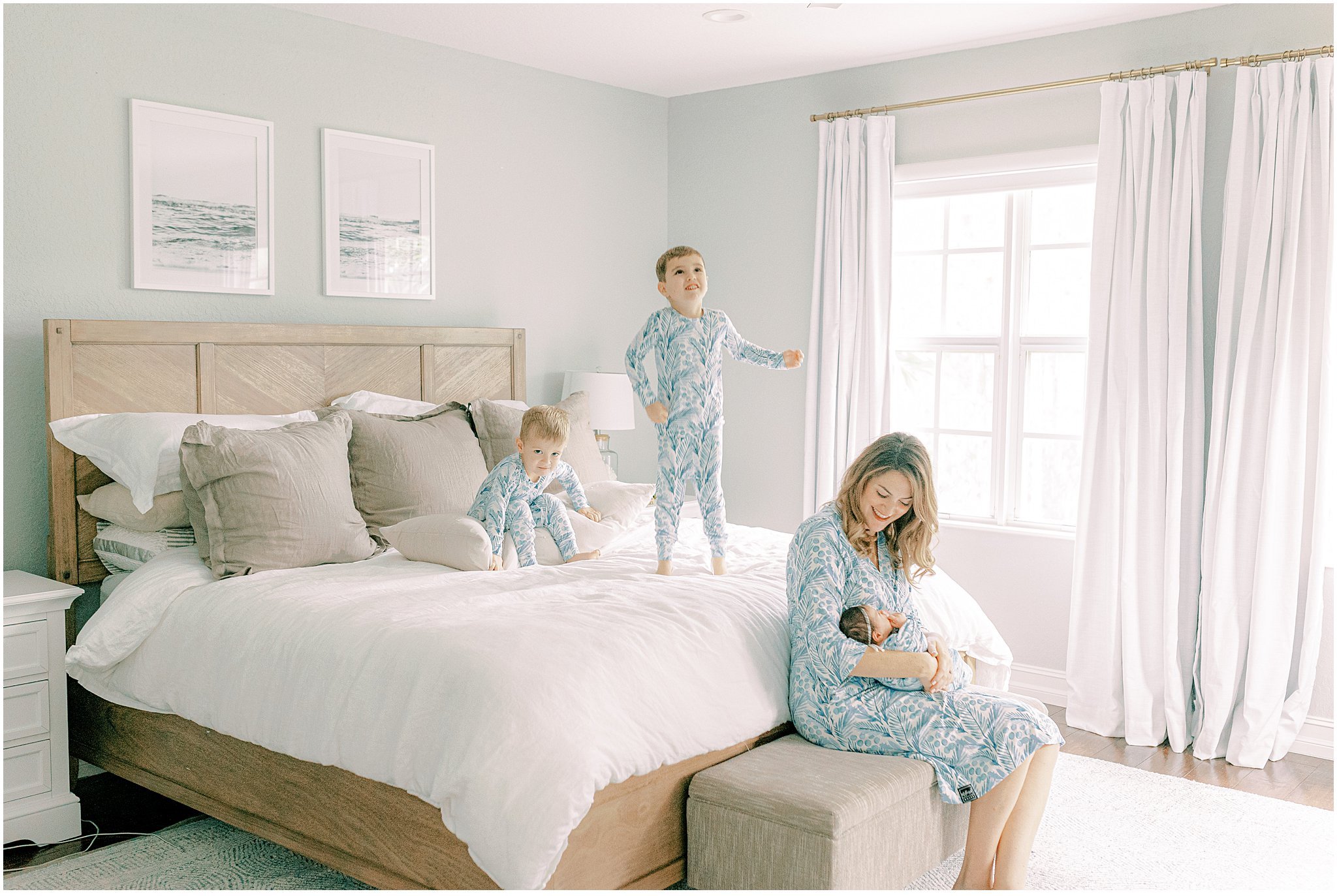 kids jumping on bed while mom holds baby